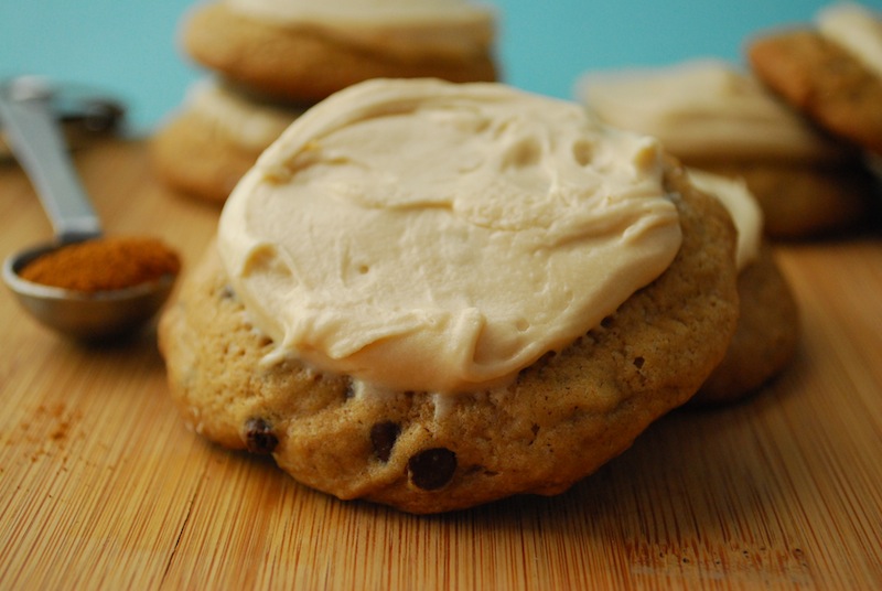 Close-up of a Mexican mocha cookie with Kahlua icing on a wooden board with more cookies and a spoon of cinnamon