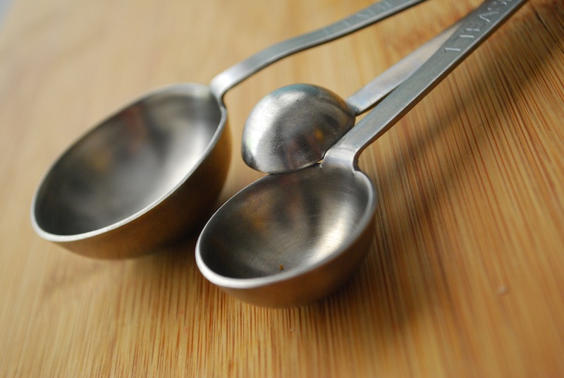 Three silver measuring spoons on a wooden background