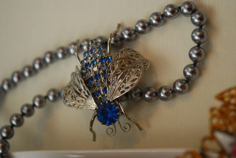 Broach in the shape of a pee, decorated with light gold and blue gemstones