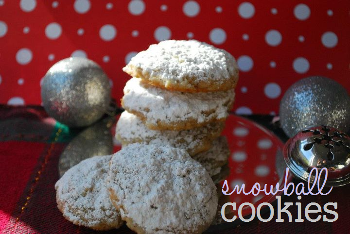 A stack of snowball cookies sitting on a holiday themed backdrop