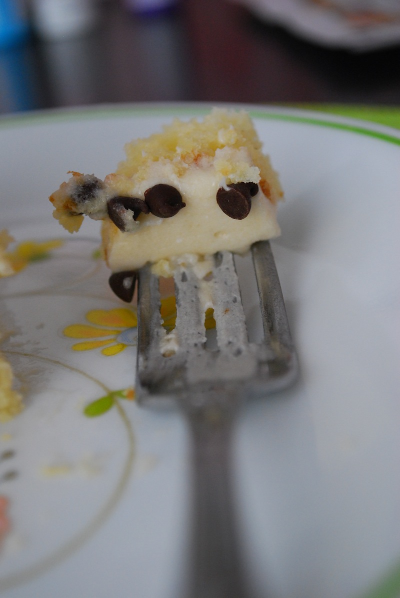 a piece of chocolate chip cookie dough cake on a fork sitting on a white plate