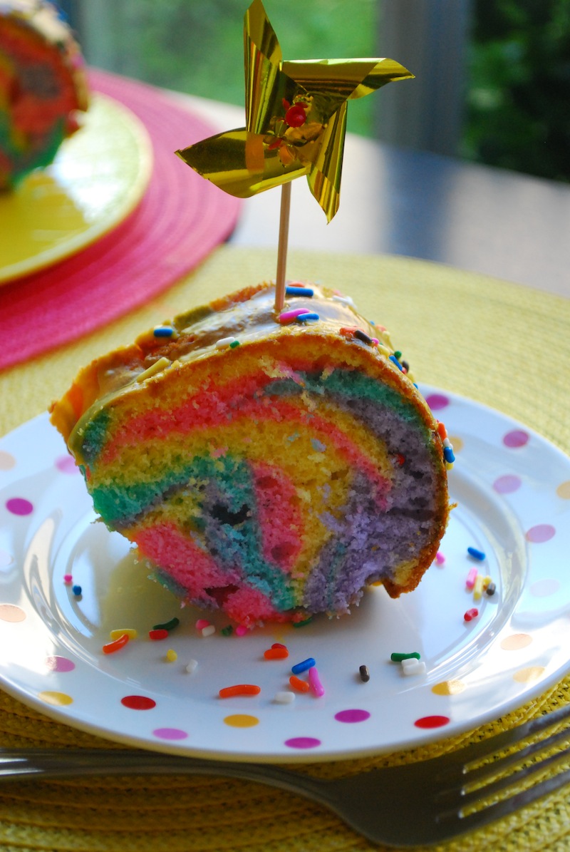 a closeup slice of a pinwheel cake piece on a polka dot plate with sprinkles