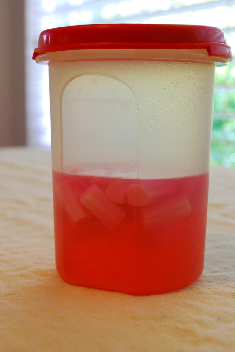 Vodka turned pink from the bubblegum pieces inside it, all in a container with a red lid