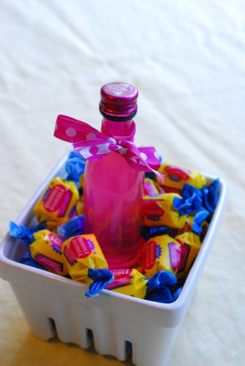 A bottle of bubblegum vodka sitting in a basket of bubblegum