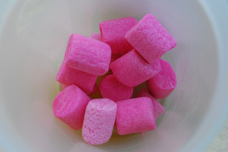 Multiple pieces of pink bubblegum at the bottom of a white container