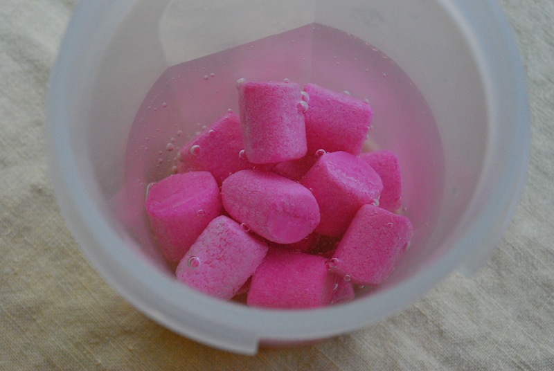 Multiple pieces of bubblegum being soaked in vodka in a white container