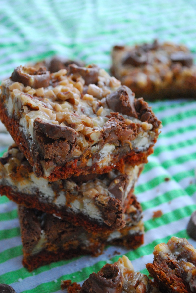 A stack of gingerbread seven layer bars on a green and white cloth