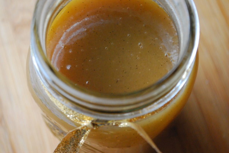 Close-up of vanilla bean butterscotch sauce in a jar with a gold ribbon