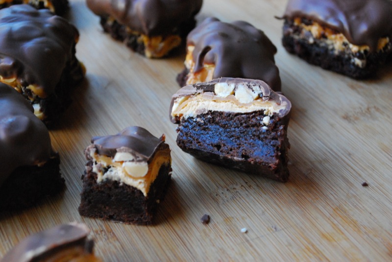 Snickers brownie bites cut open on a wood background