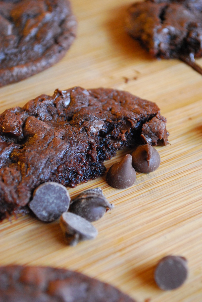 closeup of a death by chocolate cookie split in half with chocolate chips scattered around it