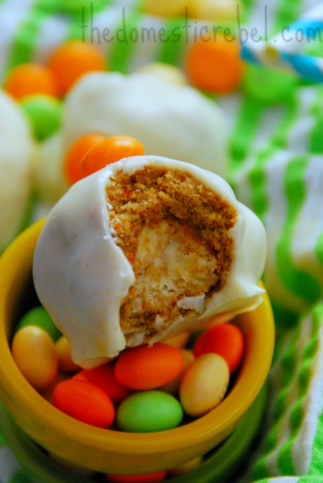 carrot cake cheesecake brownie bombs with a bite removed on a dish filled with miniature M&M's
