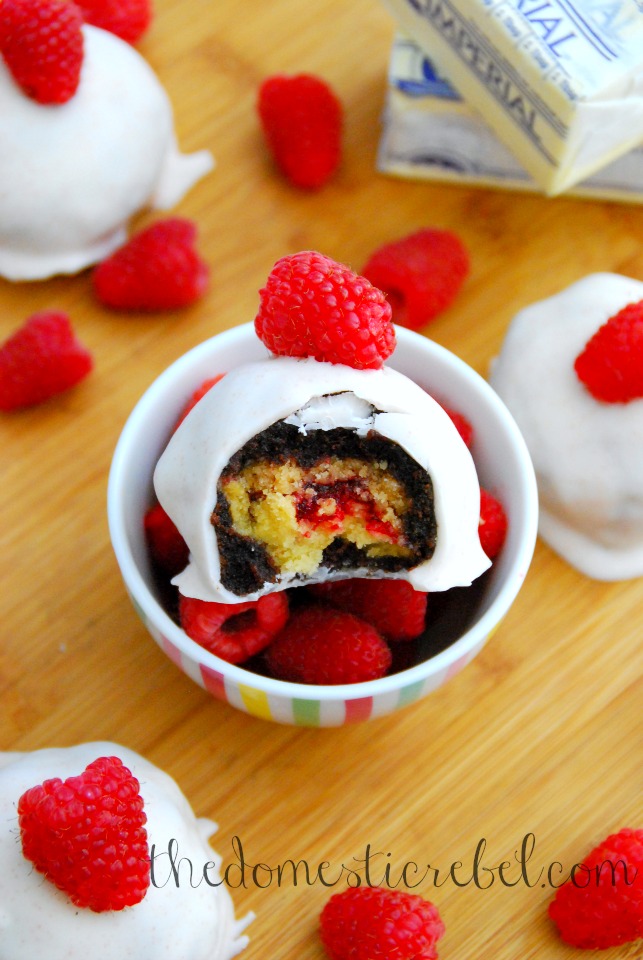 raspberry pie brownie bombs with a bite removed in a dish of raspberries