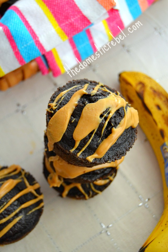 skinny chocolate peanut butter muffins stacked on white background with a banana