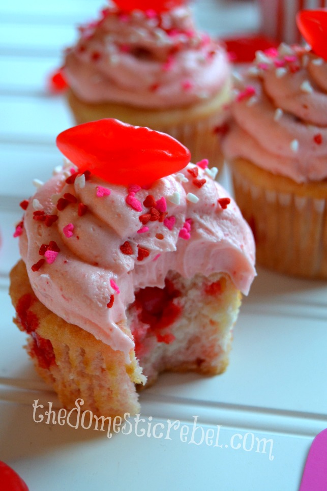 red hot cinnamon cupcakes with bite removed on white background