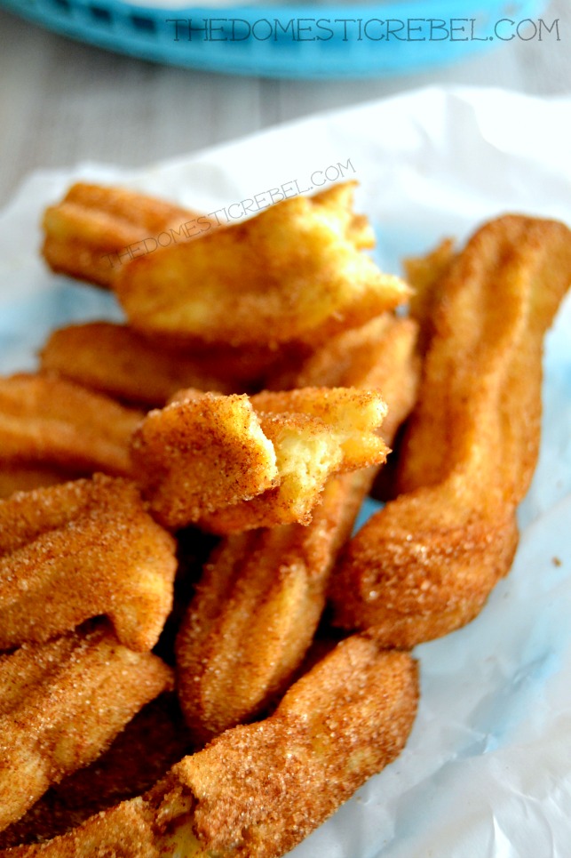 homemade churros with bite removed piled in a basket