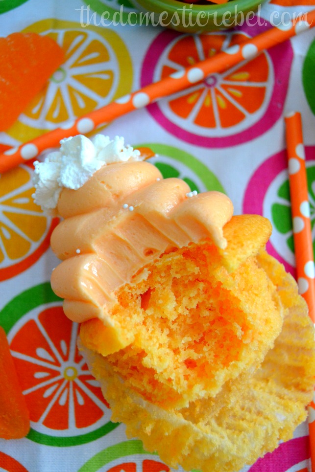 orange creamsicle cupcake with bite removed on bright dishtowel 