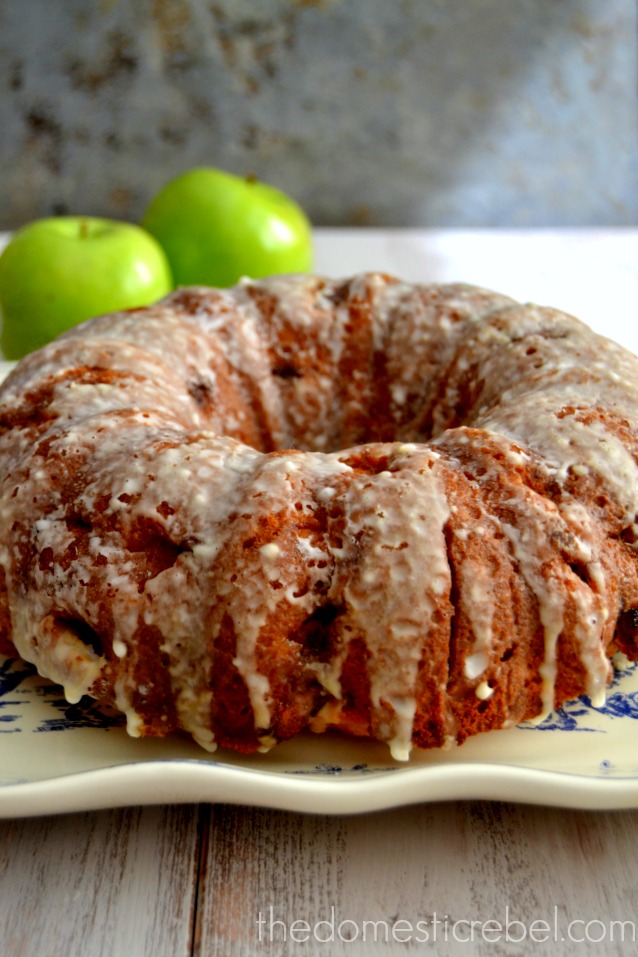 apple fritter cake on white plate with two green apples in background