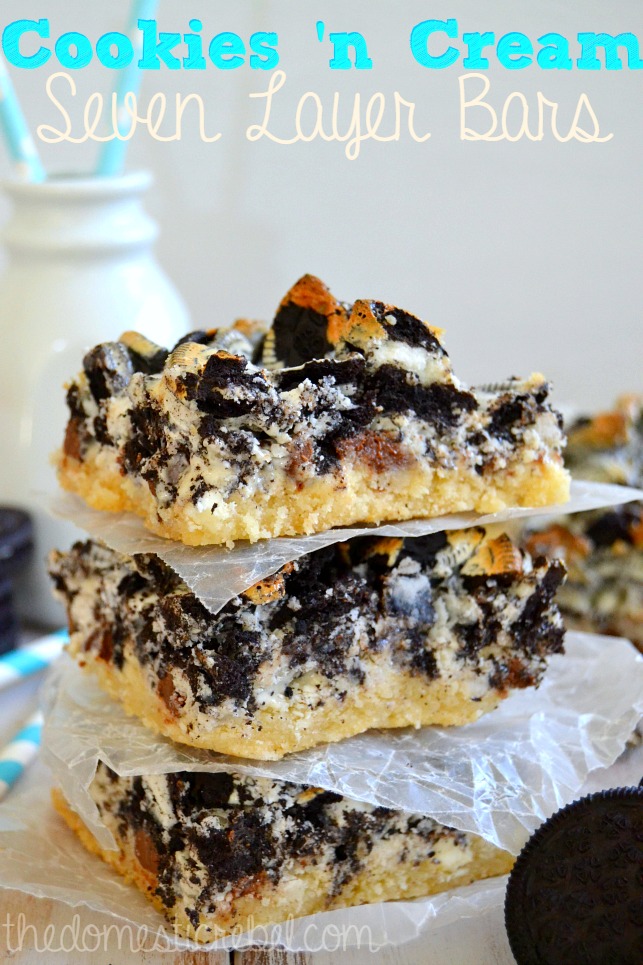 cookies n cream seven layer bars stacked between parchment on white background