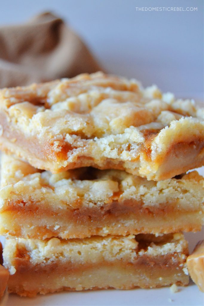 a trio stack of salted caramel butter bars. the top bar has a bite missing from it.