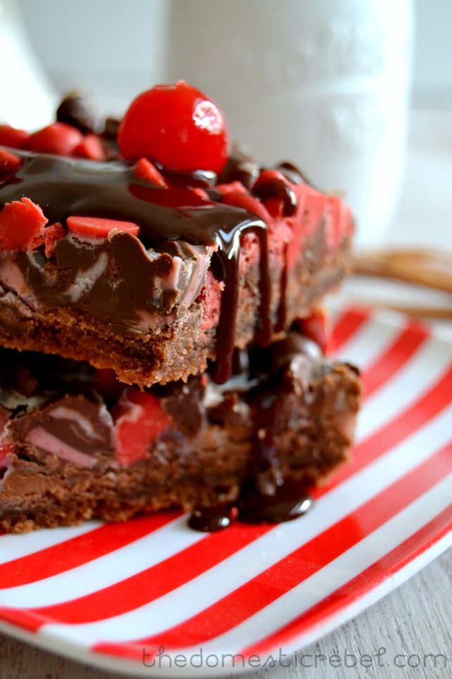 chocolate cherry seven layer bars stacked on a red and white plate with chocolate sauce on top