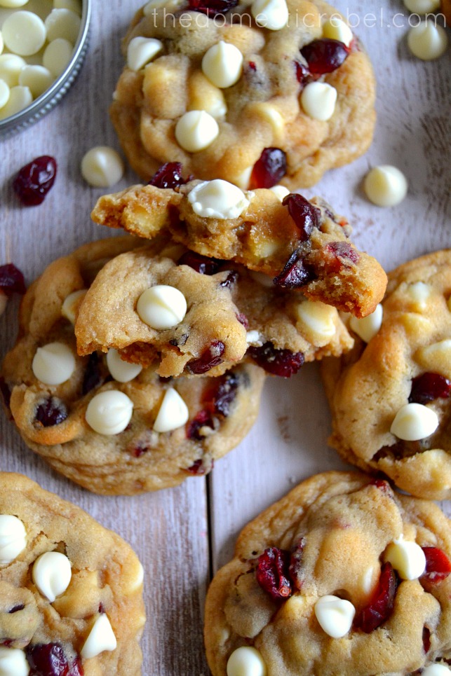 an arrangement of white chocolate cranberry cookies on a wood background with white chips and cranberries