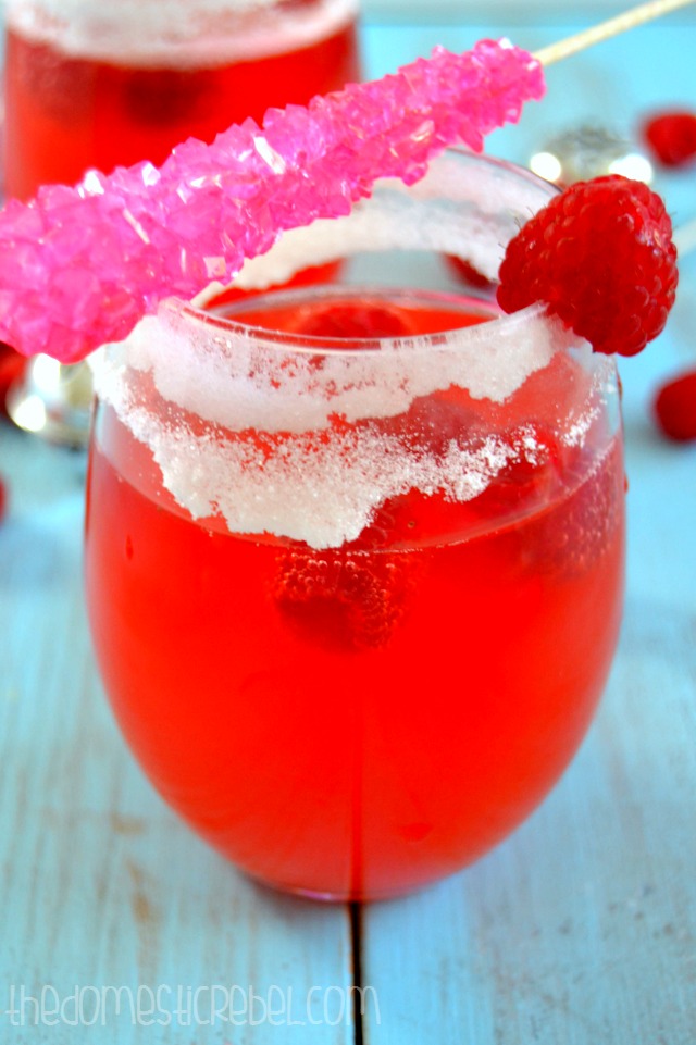 Raspberry Candy Champagne Punch with rock candy stirrer on top of glass