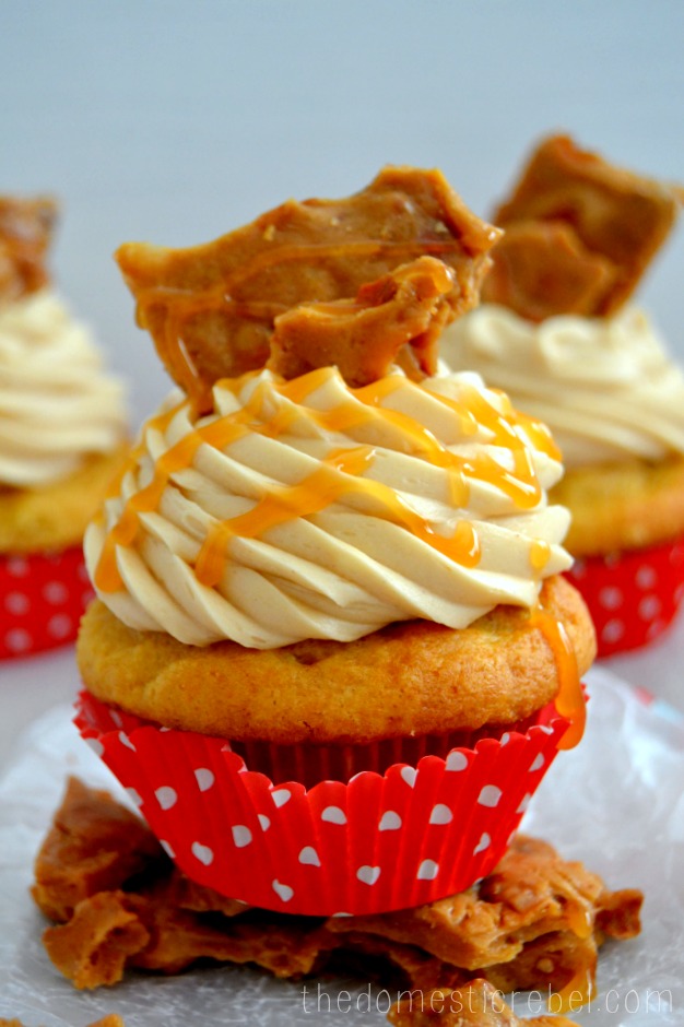 Peanut Brittle Cupcake sitting on peanut brittle clusters against white background