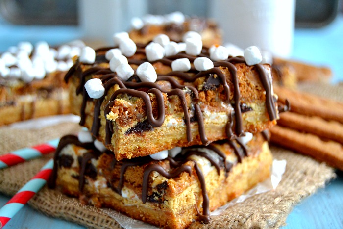 Biscoff Smores Seven Layer Bars stacked on burlap with straws and cookies