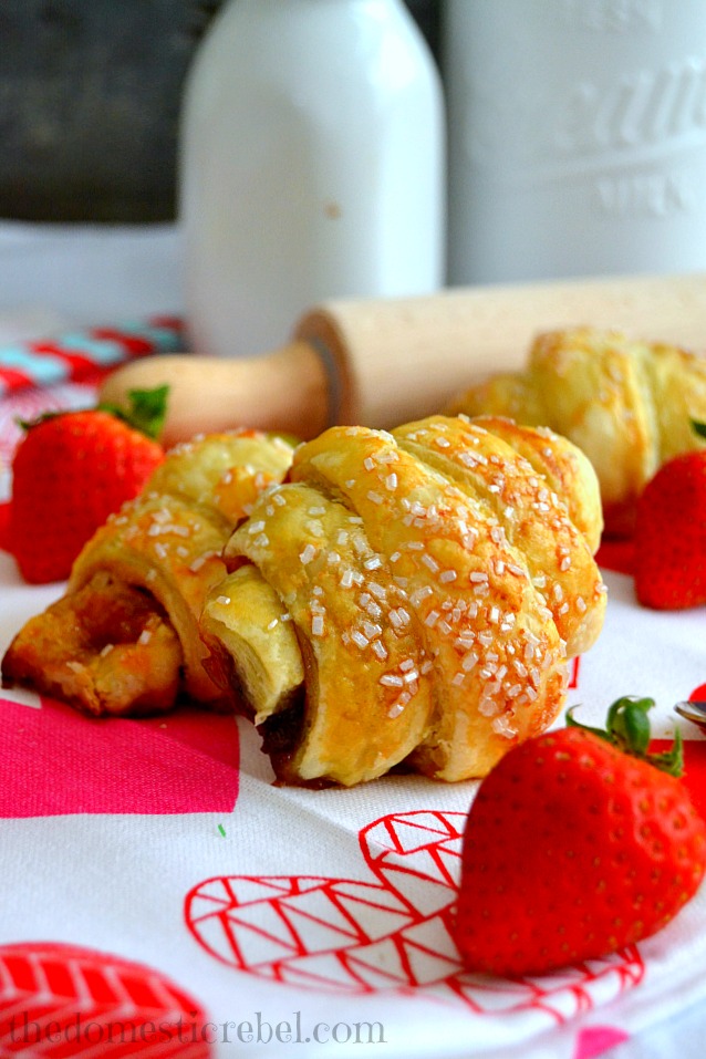 Strawberry & Nutella Croissants arranged on pink and white fabric with strawberries and milk bottles