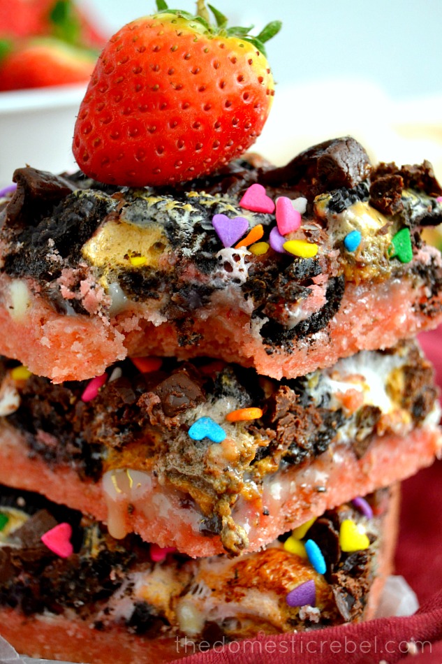 Neapolitan Seven Layer Bars stacked up close with bite removed and a strawberry on top