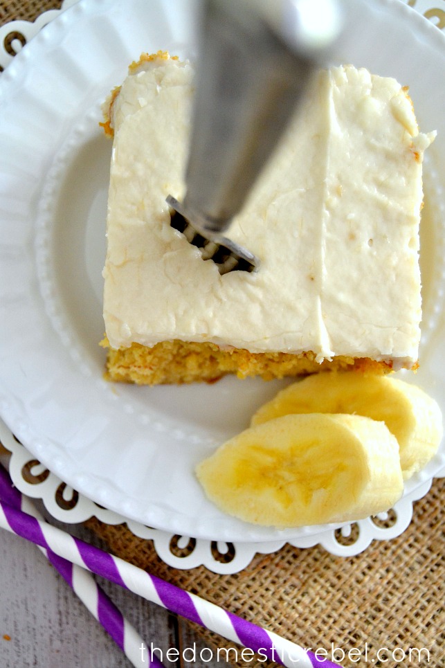 Best Banana Cake with Banana Frosting on white plate with banana slices and a fork sticking out