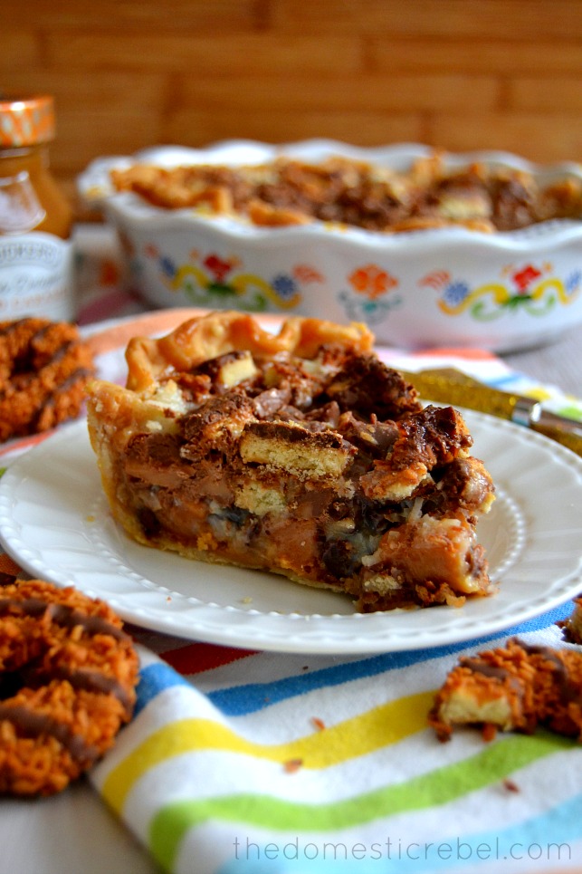 Samoas Magic Bar Pie on plate with pie dish and cookies in background