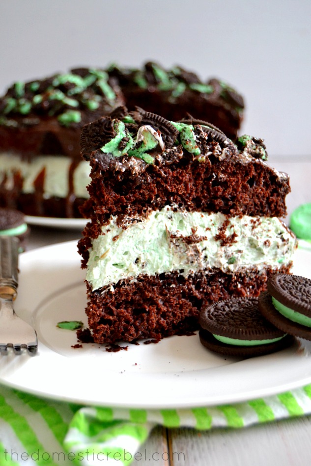 slice of mint oreo overload cake on a white plate with mint oreos and a fork