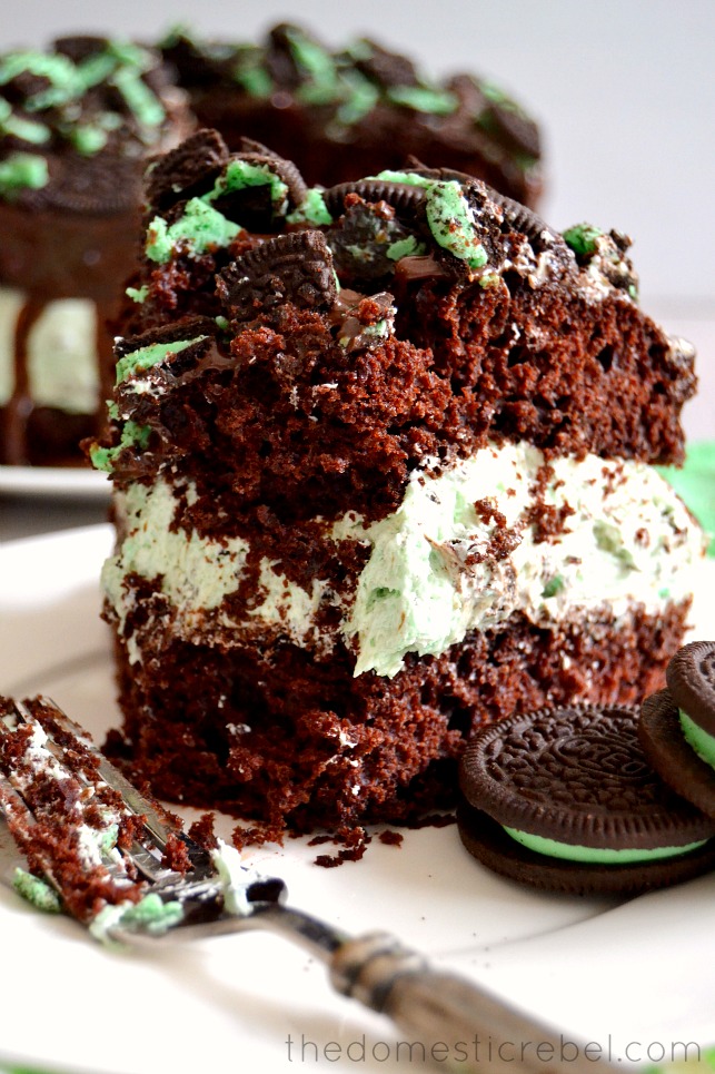 closeup photo of mint oreo overload cake on white plate with fork and an oreo cookie