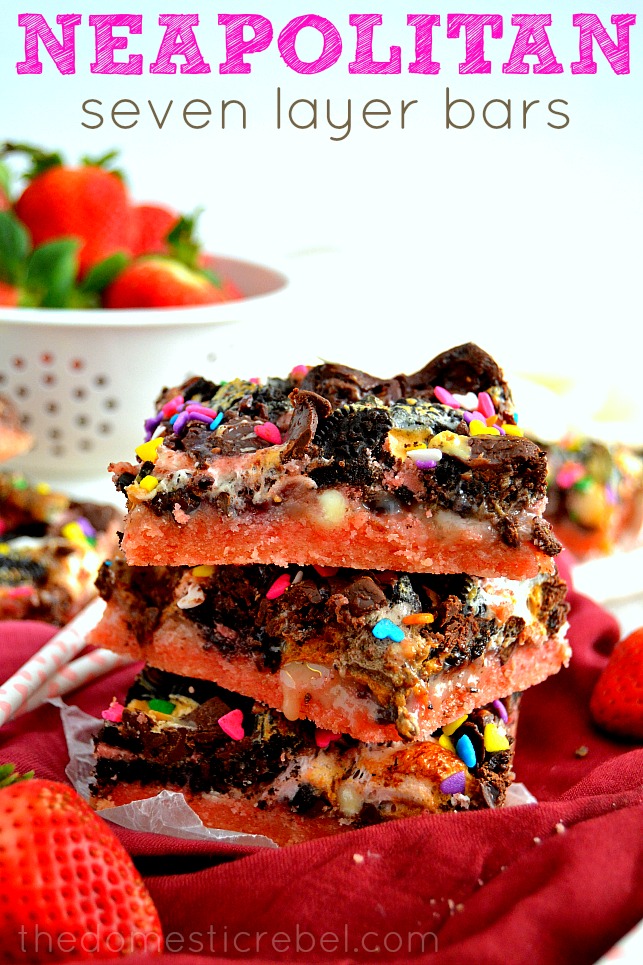 Neapolitan Seven Layer Bars stacked on red and white background with fresh strawberries