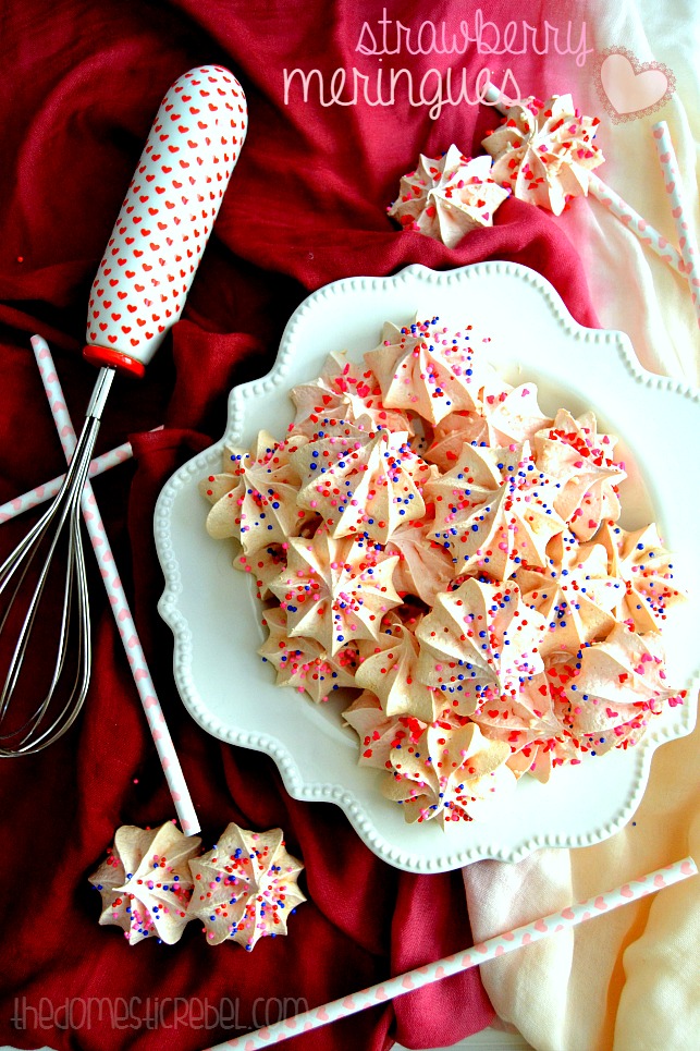 Strawberry Meringues arranged on white plate with a whisk and red fabric