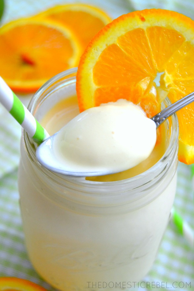closeup of spoonful of orange julius to show texture with green straw and orange slices