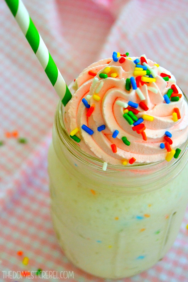 birthday cake frappuccino in glass with green straw on a pink background