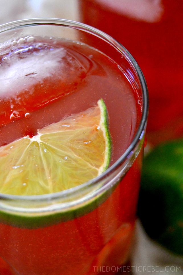 Closeup of a glass of cherry rum punch with a lime wedge inside