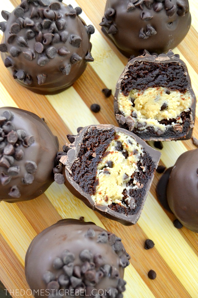 No-Bake Cookie Dough Brownie Bombs arranged on wood with one cut open to reveal inside