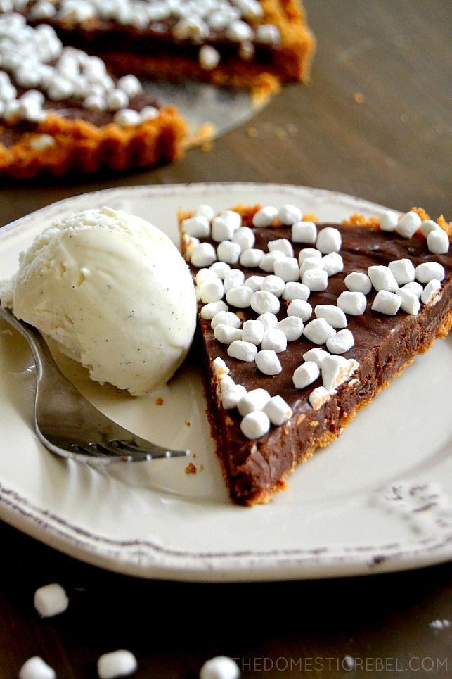 Slice of s'mores tart on white plate with ice cream
