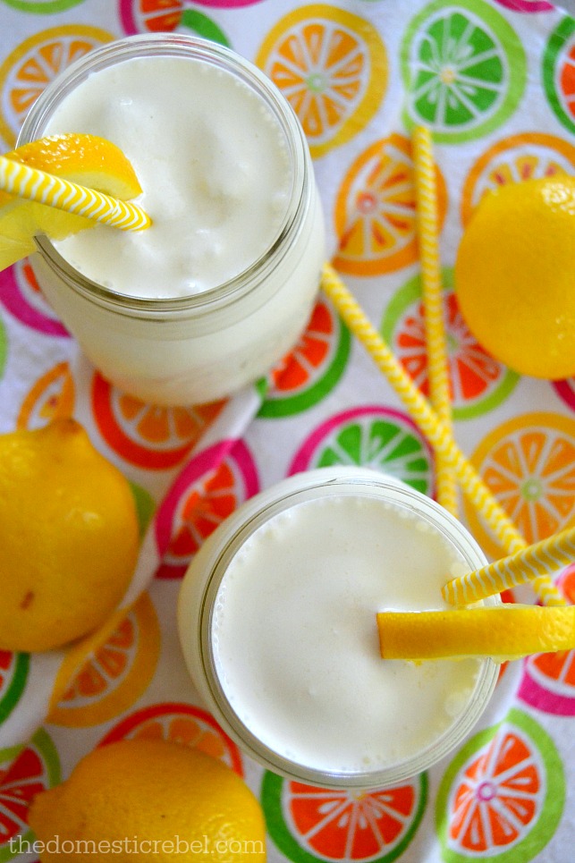 Frosted Lemonades in jars with lemons, yellow straws on citrus-print fabric