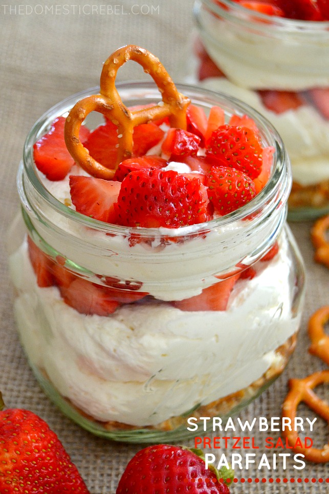 Strawberry Pretzel Salad Parfaits in jar on burlap with strawberries and pretzels scattered
