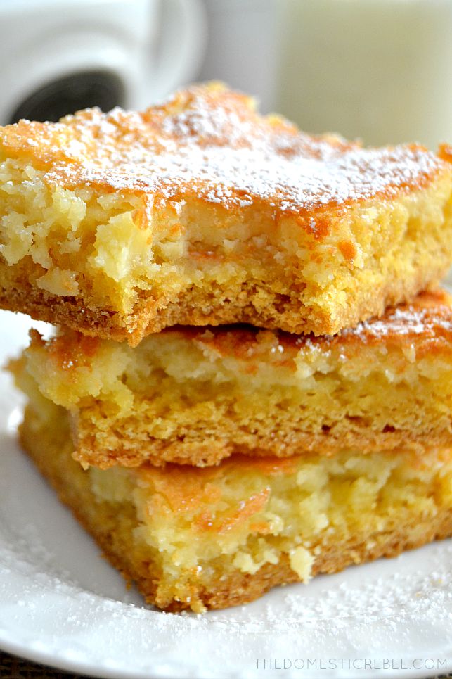 Gooey Butter Cake Bars stacked with bite missing on white plate