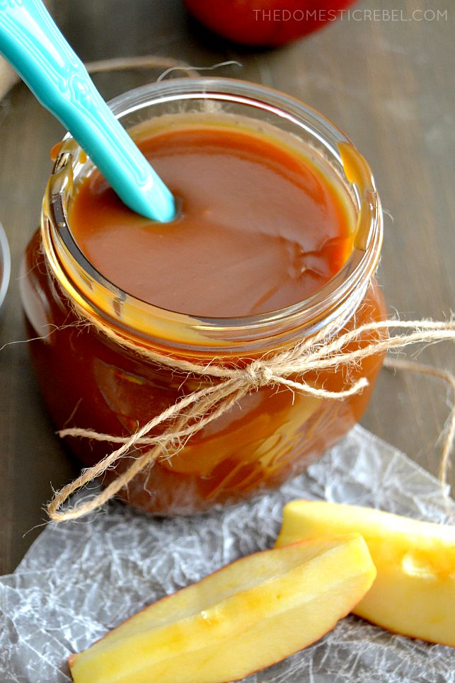 Salted Caramel Sauce in jar with apple slices and a blue spoon