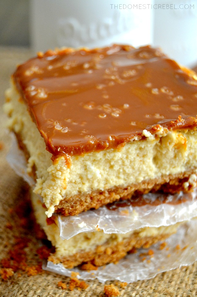 dulce de leche cheesecake bars stacked between parchment paper on burlap fabric