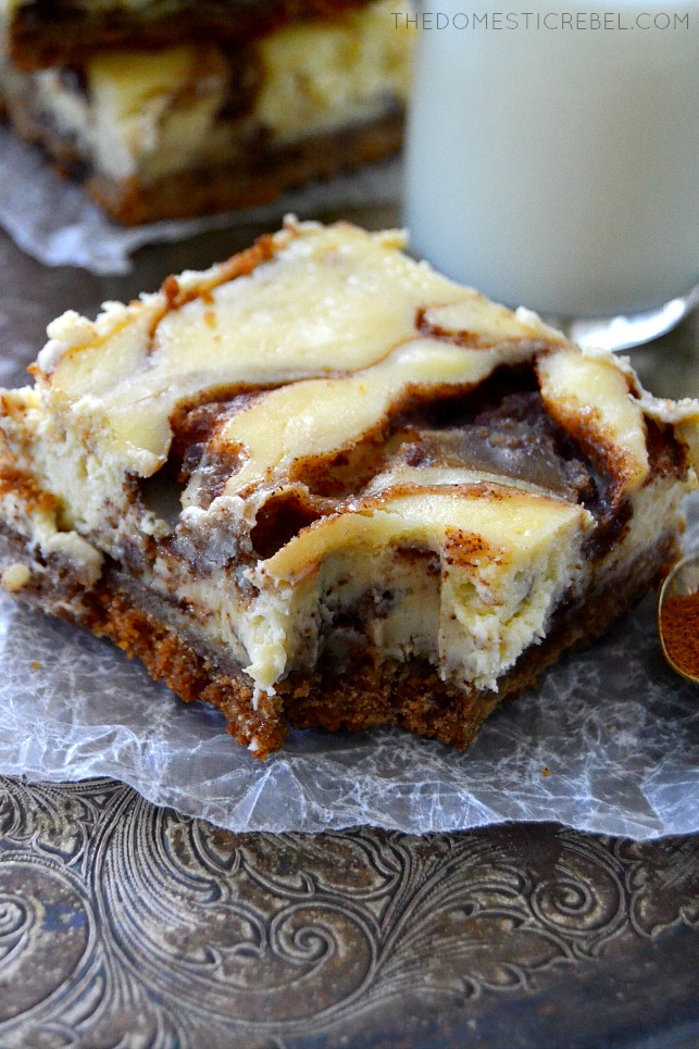 Cinnamon Roll Cheesecake Bar arranged on parchment paper with bite missing