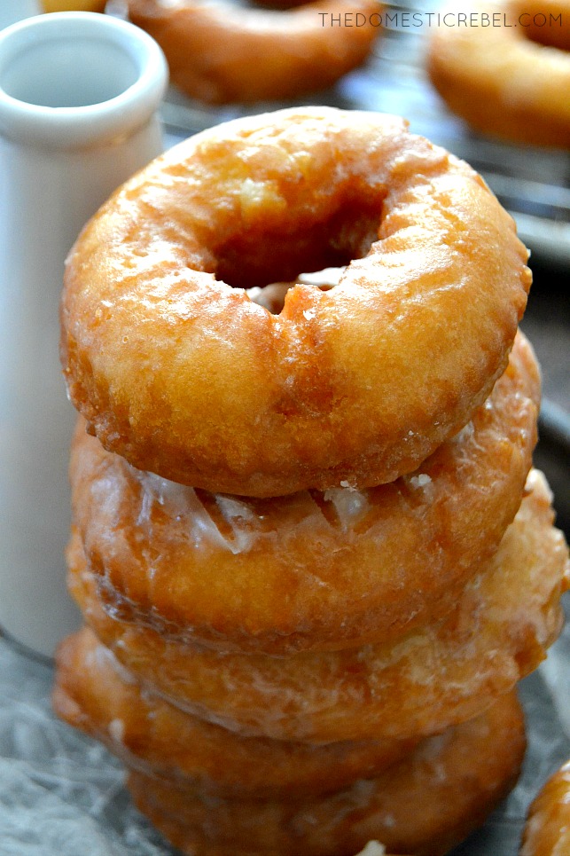 Old-Fashioned Buttermilk Doughnuts stacked on parchment with milk bottle in background