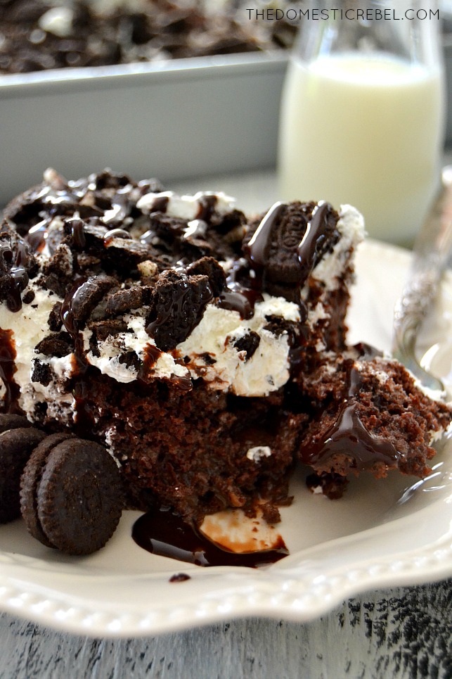 Oreo Poke Cake on white plate with fork and milk in background