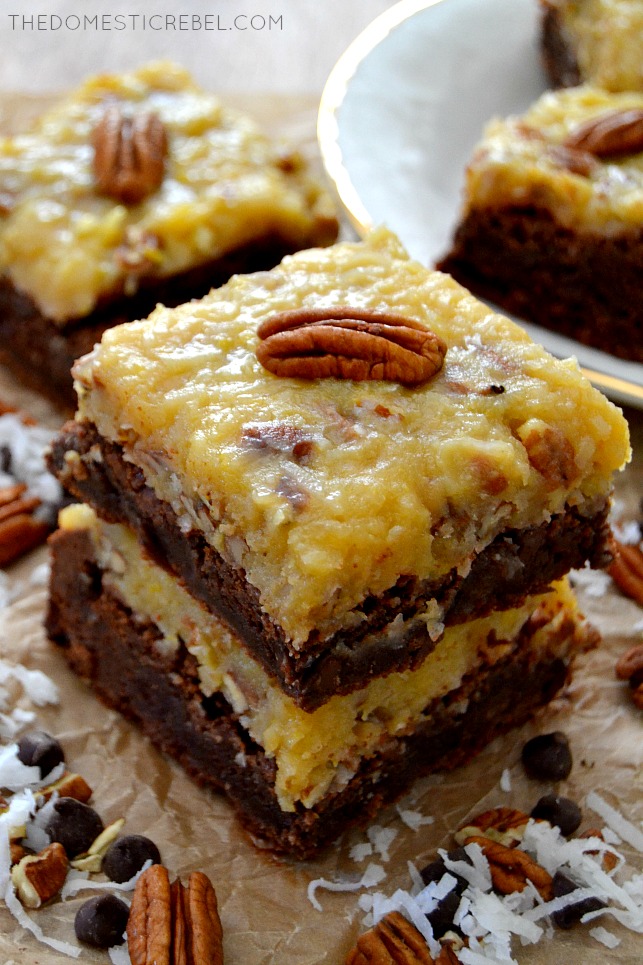 German Chocolate Brownies stacked on parchment with coconut, pecans and chocolate chips